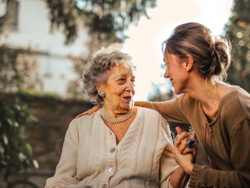 joyful adult daughter greeting happy surprised senior mother in garden
