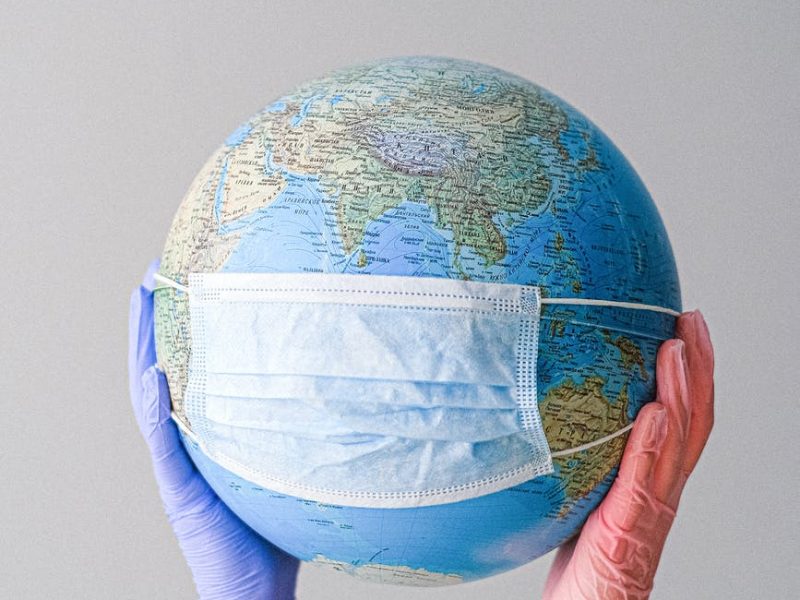 hands with latex gloves holding a globe with a face mask